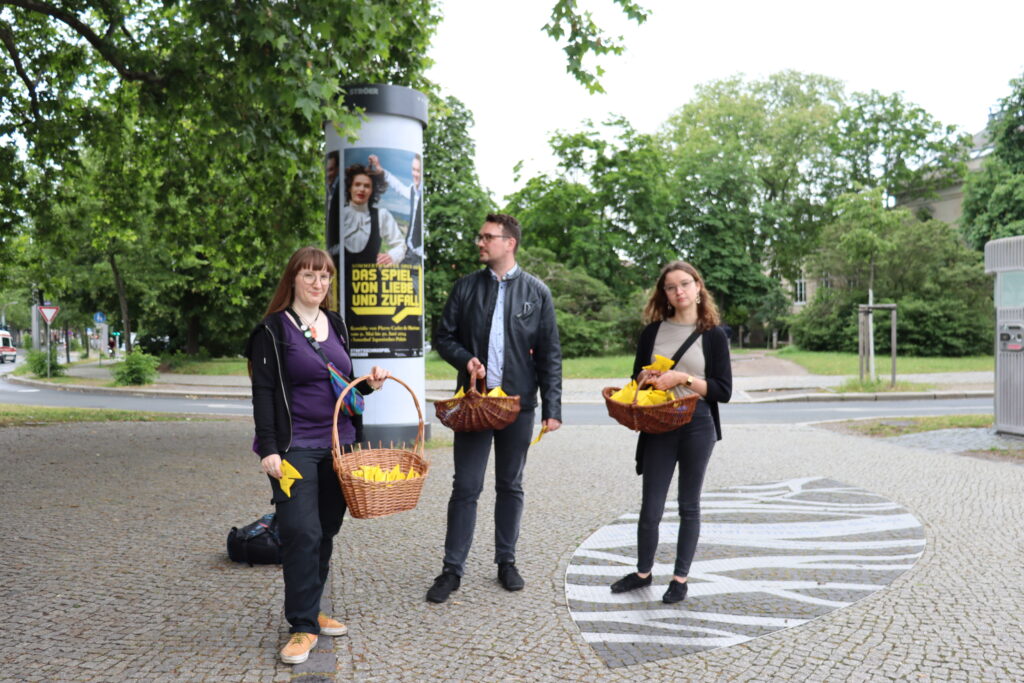 3 Personen, Stephanie, Manuel und Anne, mit Körben und gelben Papierbooten darin am Albertplatz.