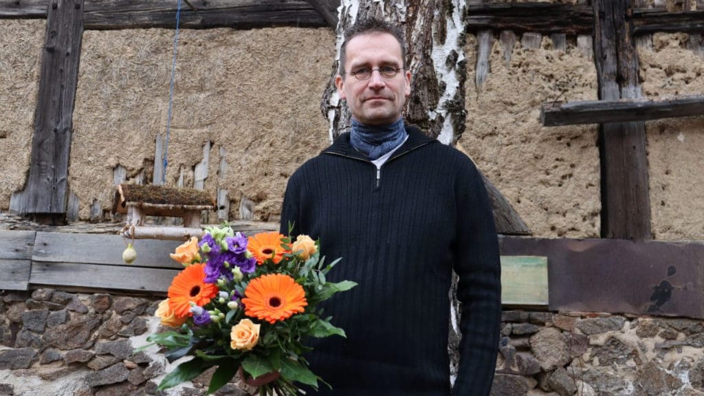 Martin Schulte-Wissermann mit einem Blumenstrauß mit orangenen Blumen.